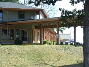 una casa con un porche y un árbol delante de él en Woodlawn Hills Motel, en Henderson