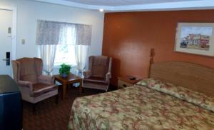 ein Hotelzimmer mit einem Bett und zwei Stühlen in der Unterkunft Woodlawn Hills Motel in Henderson