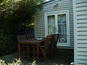 una mesa de madera y sillas fuera de una casa en Clarence Cottage en Christchurch