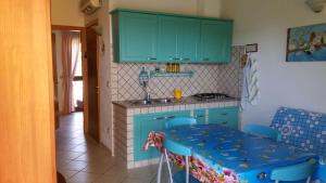 卡拉賽達的住宿－LE SALINE，厨房配有绿色橱柜和一张带蓝色椅子的桌子