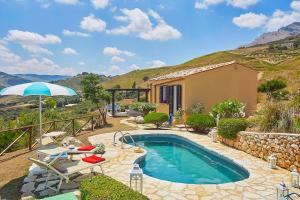 a swimming pool with chairs and an umbrella and a house at Villa Delfino - Scopello-Villas in Scopello