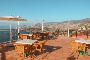 a patio with tables and chairs and a view of the city at Ocean Gardens in Funchal