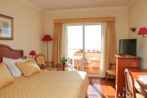 a hotel room with a bed and a television at Ocean Gardens in Funchal