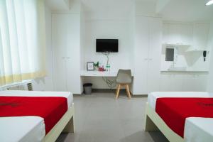 Dieses weiße Zimmer verfügt über 2 Betten und einen TV. in der Unterkunft RedDoorz Plus @ Roxas Street Davao in Davao City