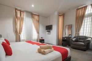 een slaapkamer met een bed, een stoel en een televisie bij RedDoorz @ Batam Center 2 in Batam Center