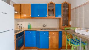 a blue kitchen with wooden cabinets and a counter at Casa Cavala by Sevencollection in Salema