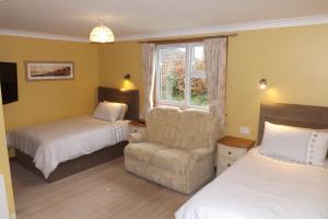 um quarto com 2 camas, uma cadeira e uma janela em The Laurels Bed & Breakfast Lodge em Omagh
