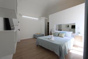 een witte slaapkamer met een bed met een kat erop bij La casa sulla scogliera in Massa Lubrense