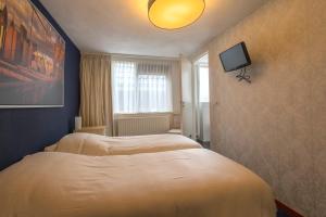 um quarto com duas camas e uma televisão na parede em De Waag em Makkum