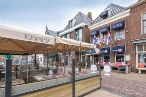 een winkel met een paraplu voor een straat bij De Waag in Makkum