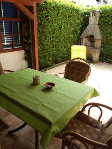 a green table with two chairs and a fireplace at APARTMAN KOREN in Malinska