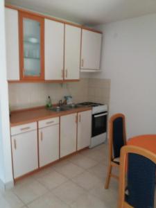 a kitchen with white cabinets and a sink and a stove at APARTMAN KOREN in Malinska +9 photos
