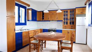 a kitchen with a wooden table and blue cabinets at Electra Village House in Apolakkiá