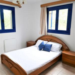 a bedroom with a bed with two blue windows at Electra Village House in Apolakkiá