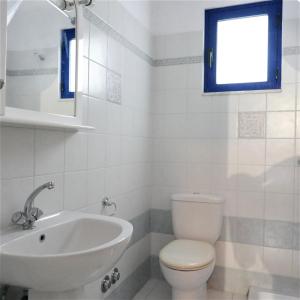a bathroom with a toilet and a sink and a window at Electra Village House in Apolakkiá +21 photos