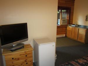 a living room with a television and a small refrigerator at Jade Mountain Motel in Chase