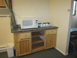 a kitchen counter with a microwave and a sink at Jade Mountain Motel in Chase