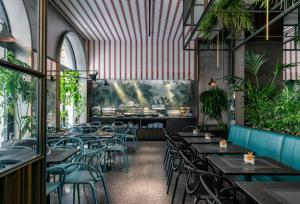 restauracja ze stołami, krzesłami i roślinami w obiekcie Hotel Sanpi Milano w Mediolanie