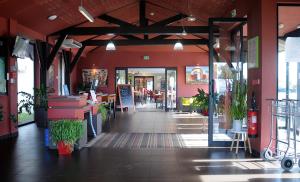 a restaurant with red walls and a hallway with plants at ibis Styles Segre in Segré