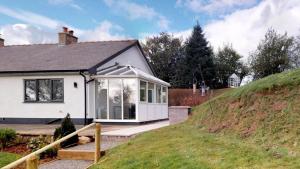 une maison blanche avec une grande fenêtre sur une colline dans l'établissement Bracdy Cottage, à Llandyrnog