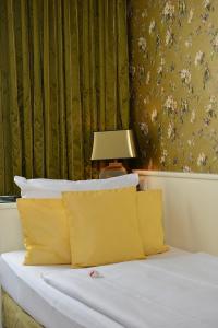 a bedroom with a bed with yellow pillows and a lamp at Hotel Domspitzen in Cologne