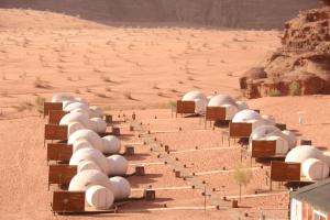 a row of white tents sitting on top of a dirt field at Wadi Rum Night Luxury Camp in Wadi Rum