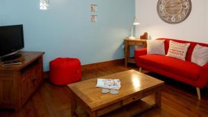uma sala de estar com um sofá vermelho e uma mesa de centro em Llety'r Adar em Port Dinorwic