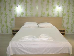 a bed with white sheets and pillows on it at Vila Verda in Eforie Nord