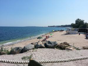 a beach with people sitting on the sand and the water at Vila Verda in Eforie Nord