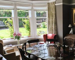 een eetkamer met een tafel, stoelen en ramen bij Glengair in North Berwick