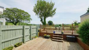 a wooden deck with a table and a fence at Ty Doli Cottage, rural location just outside Conwy town in Llangelynin