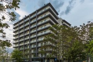 Un edificio alto con árboles delante. en AQUARIUS: Upscale Flat in the Heart of Bucharest!, en Bucarest