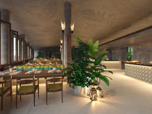 a restaurant with a table and chairs and a plant at Cinnamon Bentota Beach - Signature Selection in Bentota