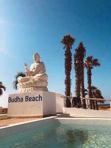 een standbeeld naast een zwembad met palmbomen bij Hotel LIVVO Budha Beach in Santa Maria