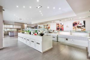 a large kitchen with white cabinets and a large island at Anna Hotel in Pefkohori