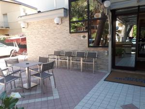 eine Terrasse mit Tischen und Stühlen vor einem Gebäude in der Unterkunft Hotel Arlecchino in Milano Marittima