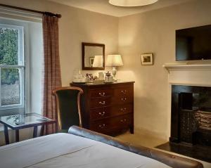a bedroom with a bed and a dresser and a fireplace at Grove House in Leyburn