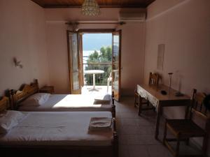 a bedroom with two beds and a table and a window at Mario Rooms in Vasiliki
