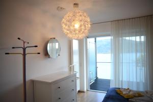 una camera da letto con lampadario pendente e comò bianco e una stanza di Seeappartement Marina a Pörtschach am Wörthersee