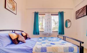 a bedroom with a bed with blue curtains and a window at West Valley Villa in Panchgani