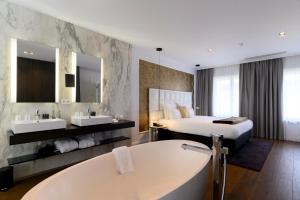 a bathroom with a tub and two sinks and a bed at Hotel Rubens-Grote Markt in Antwerp