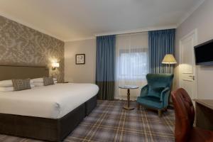 ein Hotelzimmer mit einem großen Bett und einem blauen Stuhl in der Unterkunft Bridgewood Manor Hotel & Spa in Chatham