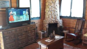 a living room with a television and a fireplace at La Casa del Carballo in Pisones
