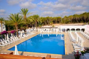 
a beach with a pool, chairs, and a pool table at Cala Llenya Resort Ibiza in Cala Llenya
