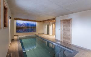 a swimming pool in a house with a painting on the wall at Odalys Chalet Le Lys in Les Deux Alpes