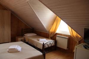 アドレルにあるVernuy Mini-hotelのベッド2台と窓が備わる屋根裏部屋です。