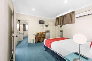 a hotel room with a bed, chair, and table at Econo Lodge Park Lane in Bundaberg