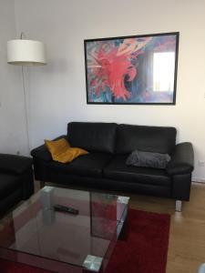 a living room with a black couch and a glass table at 3-Zimmer Ferienwohnung Bahnhofsnähe in Fulda