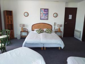 una camera da letto con un letto con lenzuola bianche e cuscini verdi di Les Rochers a Carnac