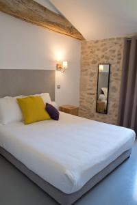 1 dormitorio con 1 cama blanca grande con almohada amarilla en Hôtel Le 23, en Sauternes